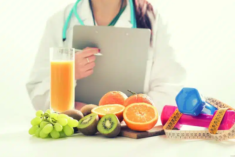 nutricionista com protocolo em mãos e mesa com alimentos funcionais para acelerar tratamentos da candidíase