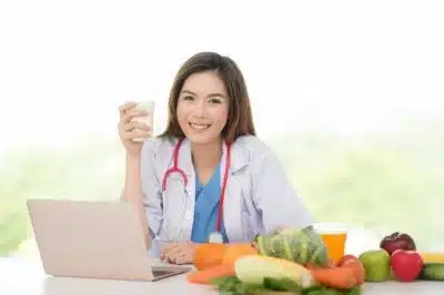 nutricionista levantando um copo em sua mesa com alimentos naturais