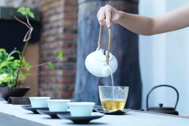 mulher servindo xicaras de chá de neem contra fungos na boca