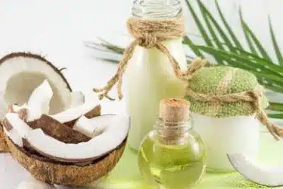 óleo de coco em frasco e pedaços de coco sob a mesa como remédio em tratamentos