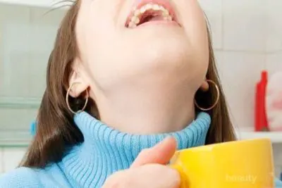 mulher fazendo o gargarejo com vinagre de maça contra a candidíase na boca