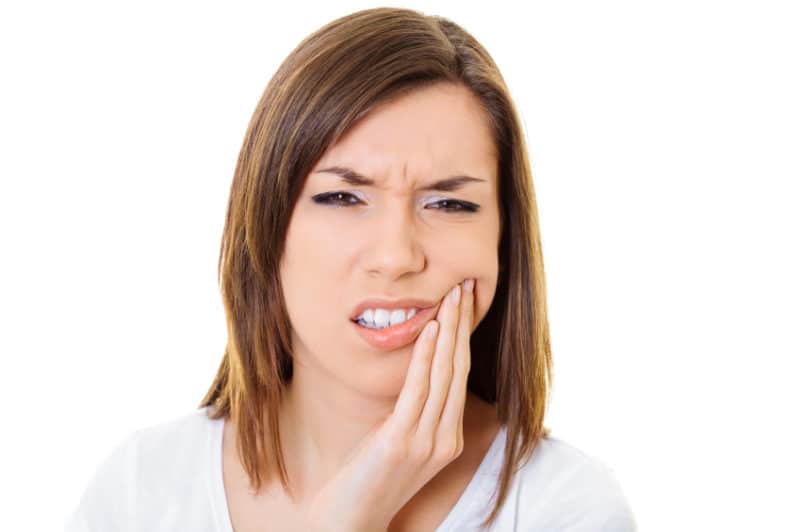 mulher sofrendo com candidíase oral com a mão na boca e cara de incomodo