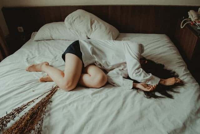 mulher na cama cansada com os sintomas incômodos da candidíase
