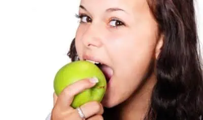 mulher comendo alimento que previne a candidíase oral