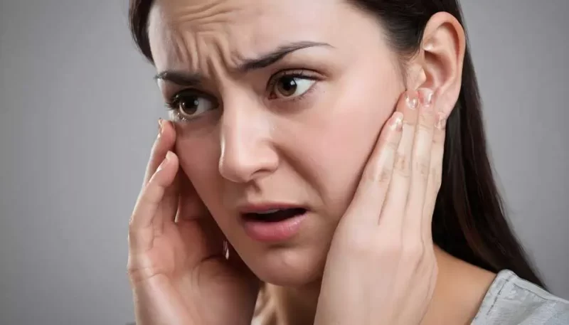 imagem de uma mulher com as mãos no ouvido sentindo encomodo com os sintomas da otomicose