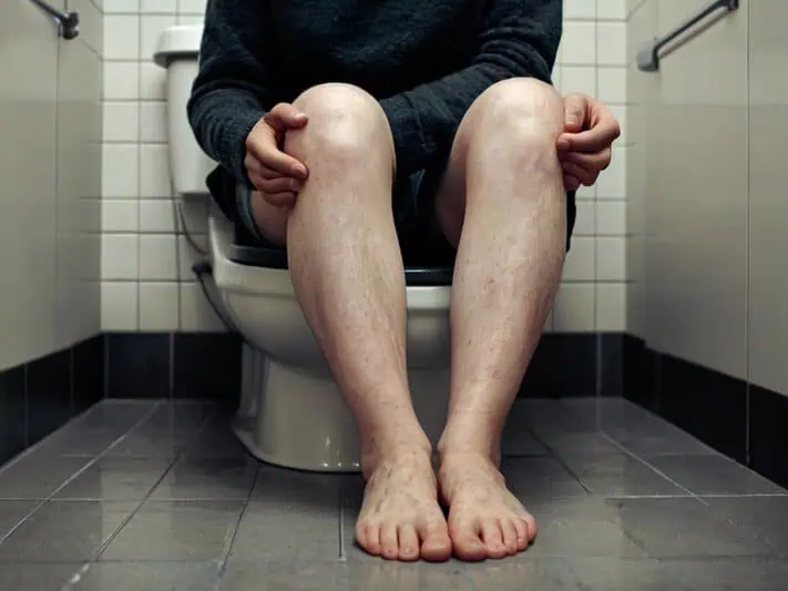foto de um homem sentado em uma privada com sintoma de candidíase e disbiose intestinal